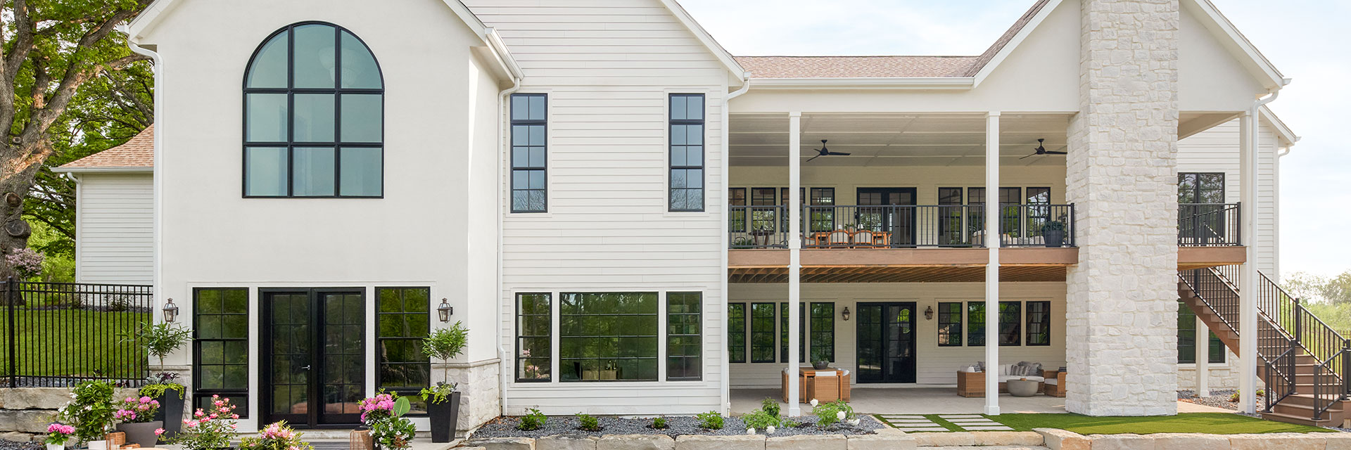 An expansive white coastal home with dual wood decks and several custom windows.