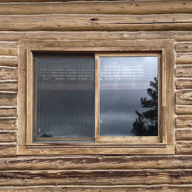 A wooden window on a log cabin wall, showcasing a before sliding window.