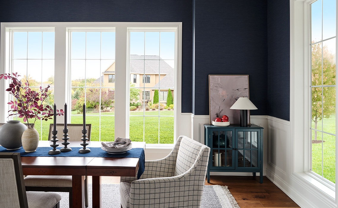 a dark blue living room featuring crisp white vinyl double-hung windows