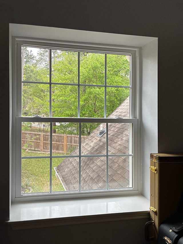 White-framed window overlooking a green yard in a Houston Woodland Home.
