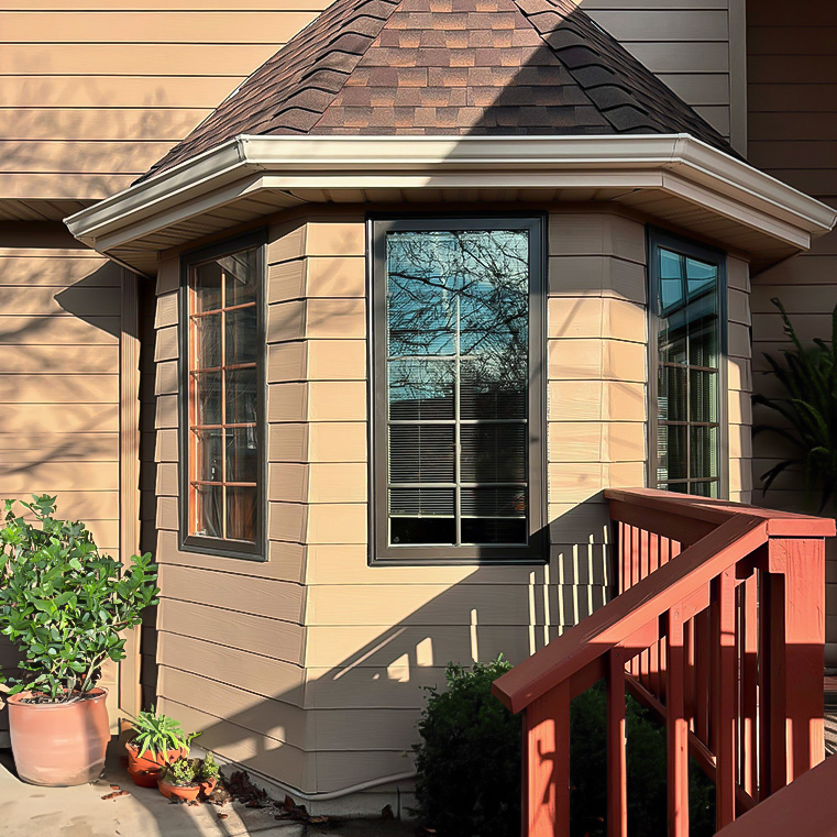 A newly installed bay window on a home exterior, showcasing replacement windows and a wooden deck.