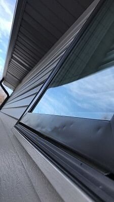 hail damage on an Omaha home window exterior with dark trim