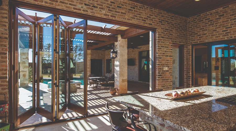 Brown bifold door on a brick home exterior that opens to a large outdoor patio.