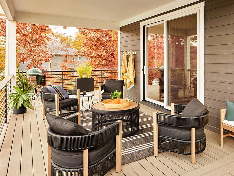 black patio furniture on an outdoor back patio with a white fiberglass sliding patio door to enter the home interior.
