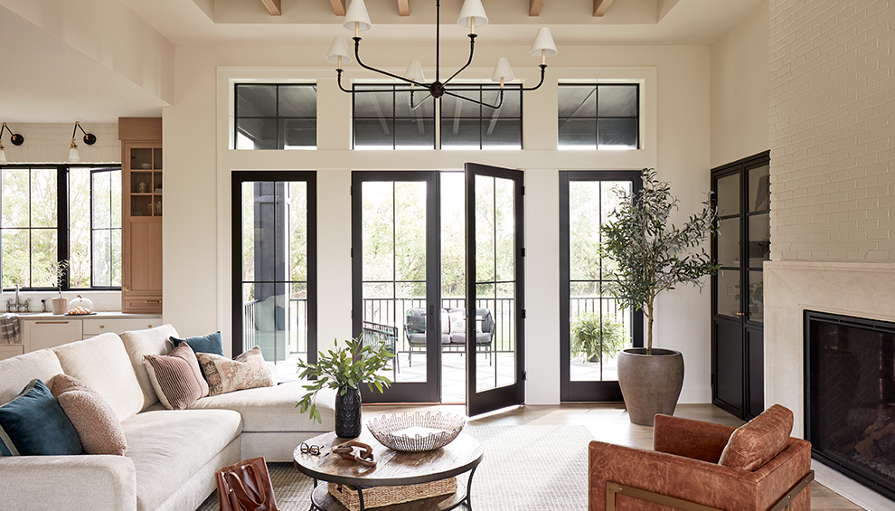 a long, wooden dining room table in front of a set of white french doors.