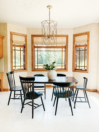 Breakfast nook with table and chairs by wood windows. 