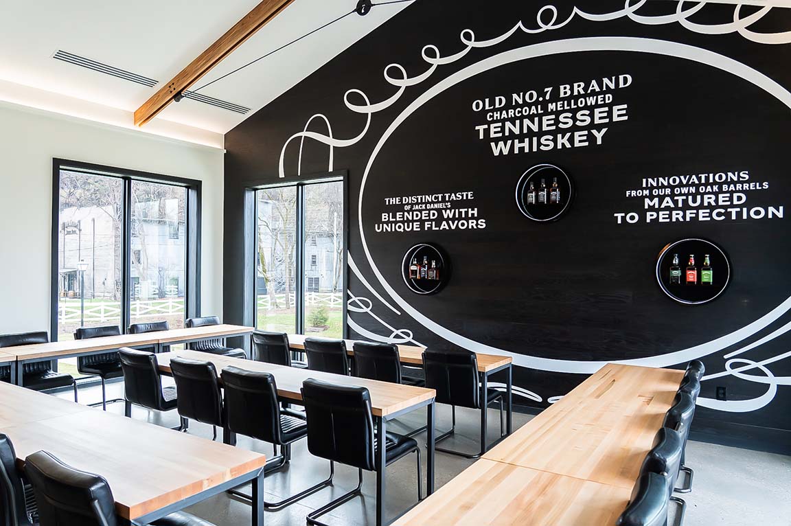 Modern whiskey tasting room with long tables and feature wall.