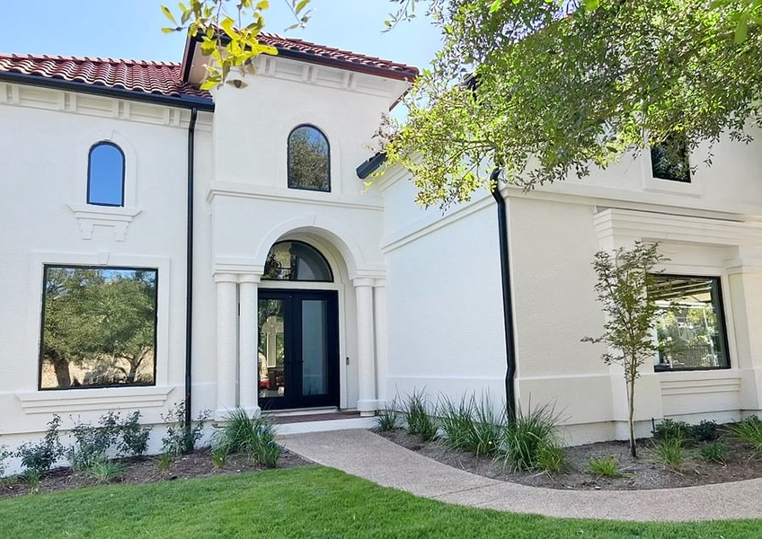 Curbside view of Spanish-style Austin home with newly installed black windows and doors. 