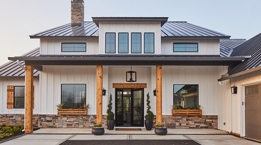 A modern house exterior featuring black windows, wooden accents, and stone details.