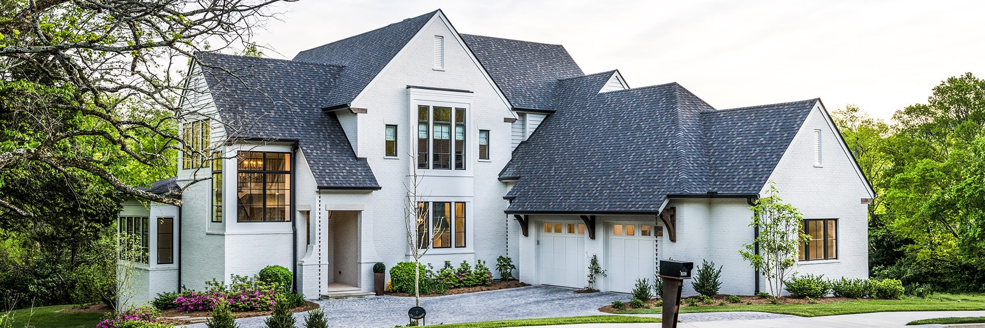 White brick house with large black windows with a traditional grille pattern.