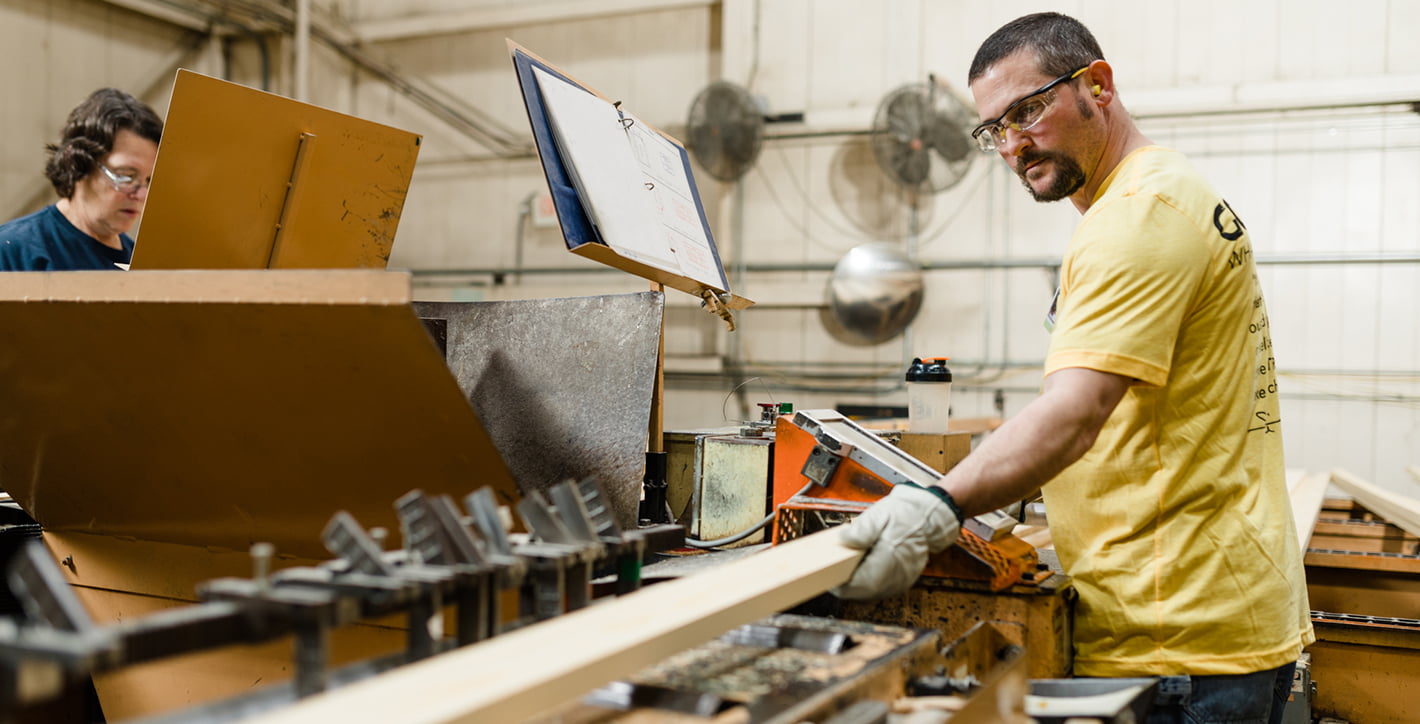 man working in the factory cutting a wood board