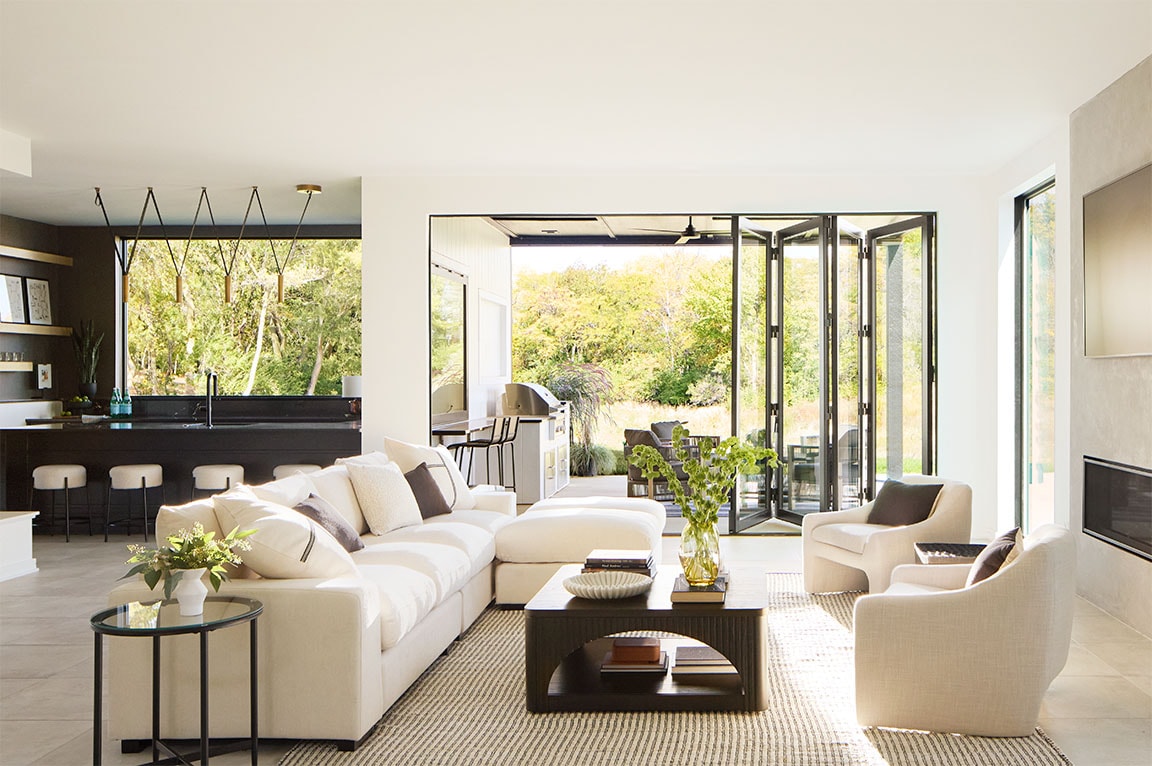 Black bifold patio doors expand the all-beige living room to a large backyard patio.