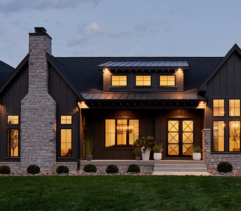 home exterior at dusk stone chimney impervia fiberglass windows