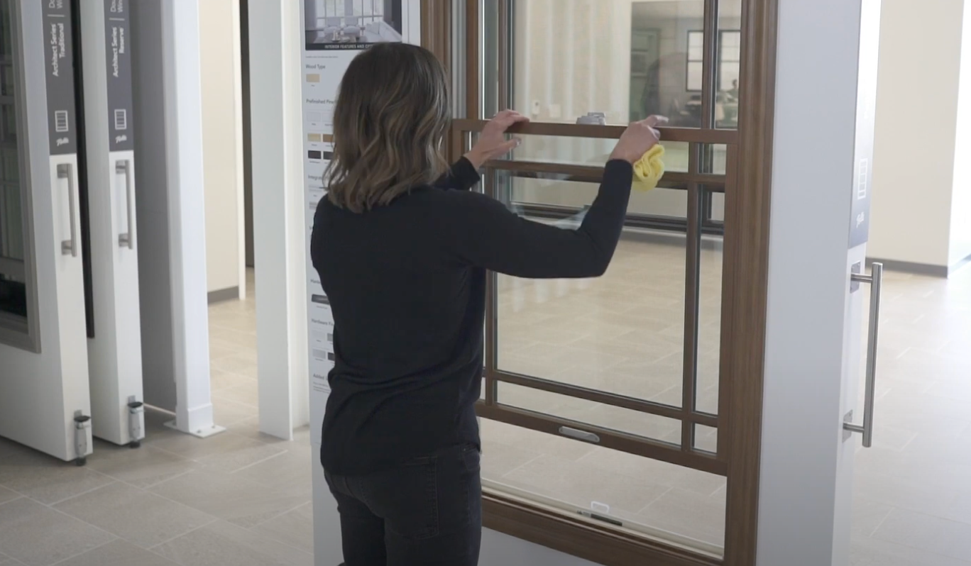 a woman is demonstrating how to clean a double-hung window