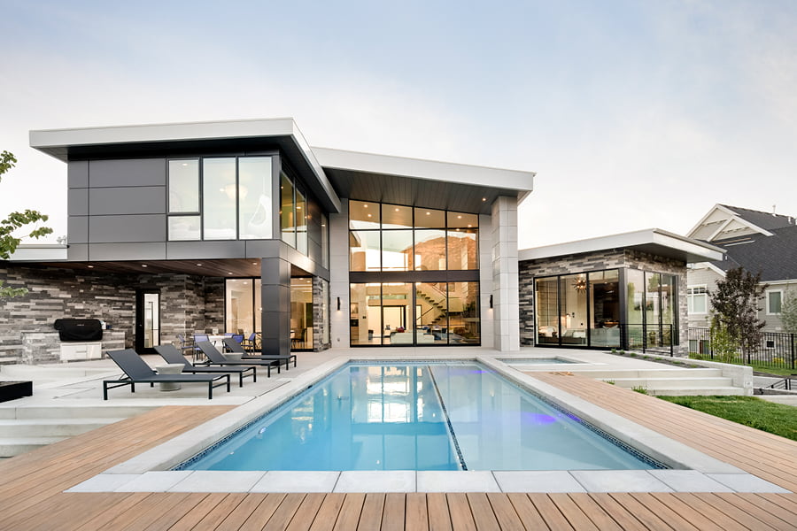 Contemporary gray home with high windows and pool in deck