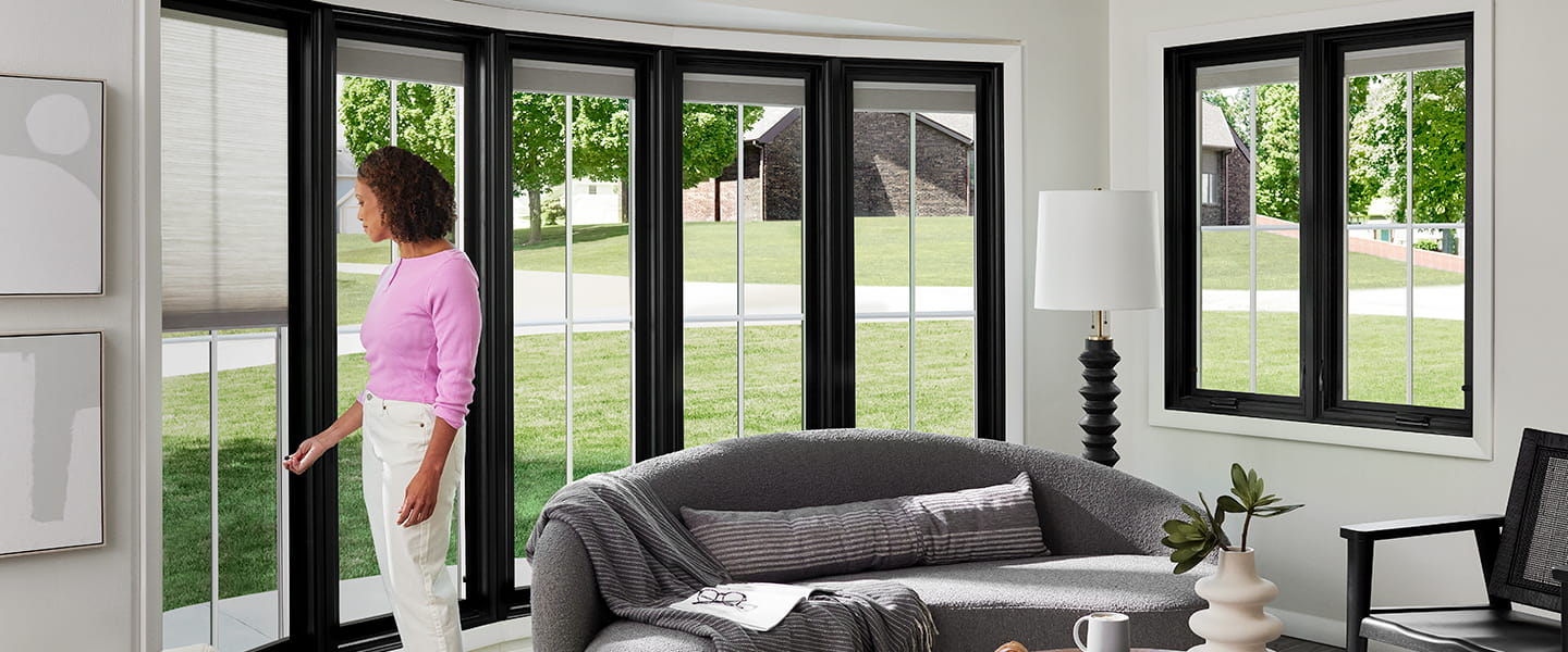 a woman adjusts the between-the-glass blinds on her Pella wood casement windows