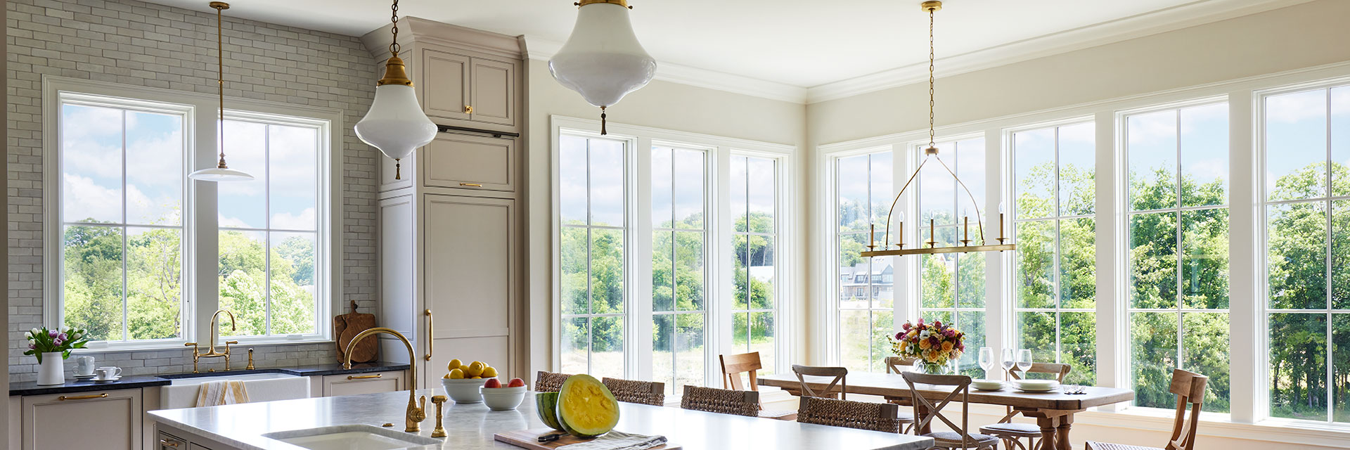 A dining room with a large island and beautiful white windows. 