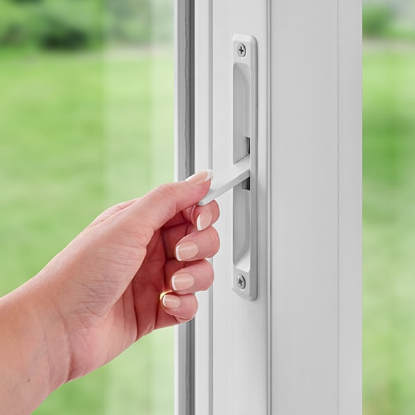 Hand engaging secondary window lock on white window frame.