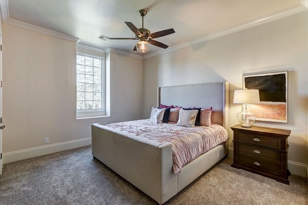 Neutral colored bedroom lit by white casement window with traditional grille pattern