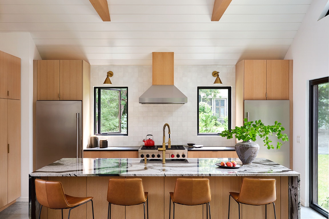A modern kitchen featuring kitchen casement windows, wooden cabinets, and a marble countertop.