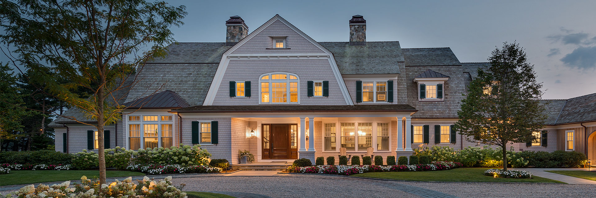Boston-area home exterior at dusk with lights from the inside emitting out the new windows.