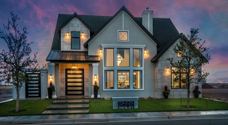 Contemporary home at sunset with light glowing from casement windows