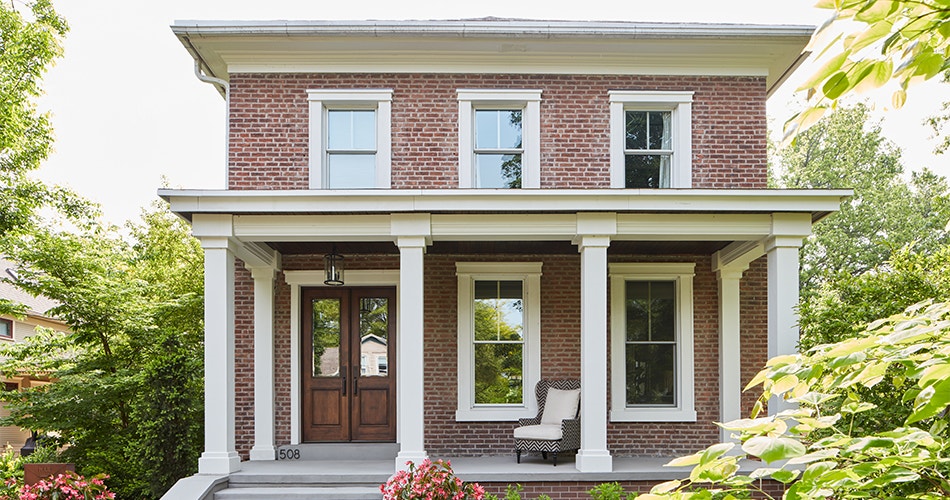 Midwestern two-story brick home with traditional windows and a wood front entry door.