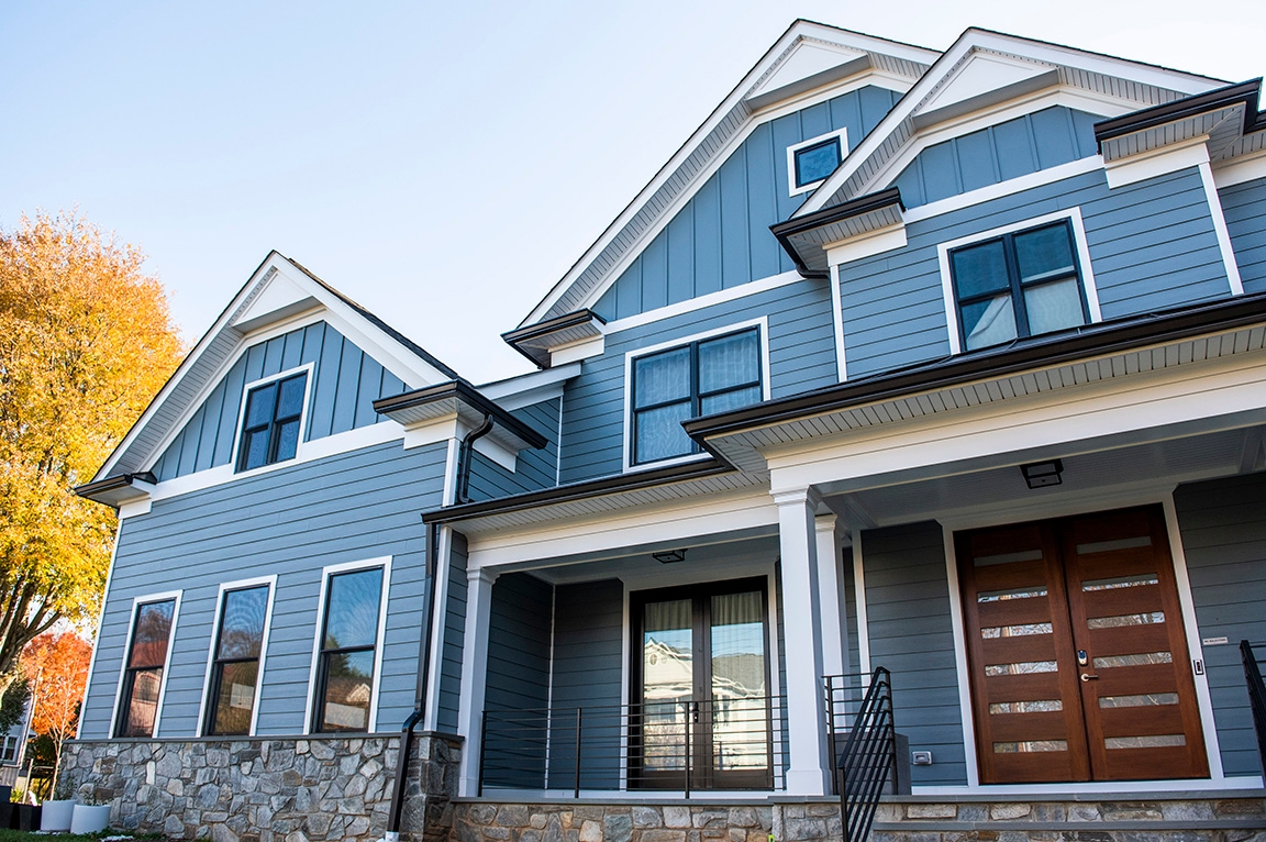 Front view of black windows featured on a blue modern farmhouse. 