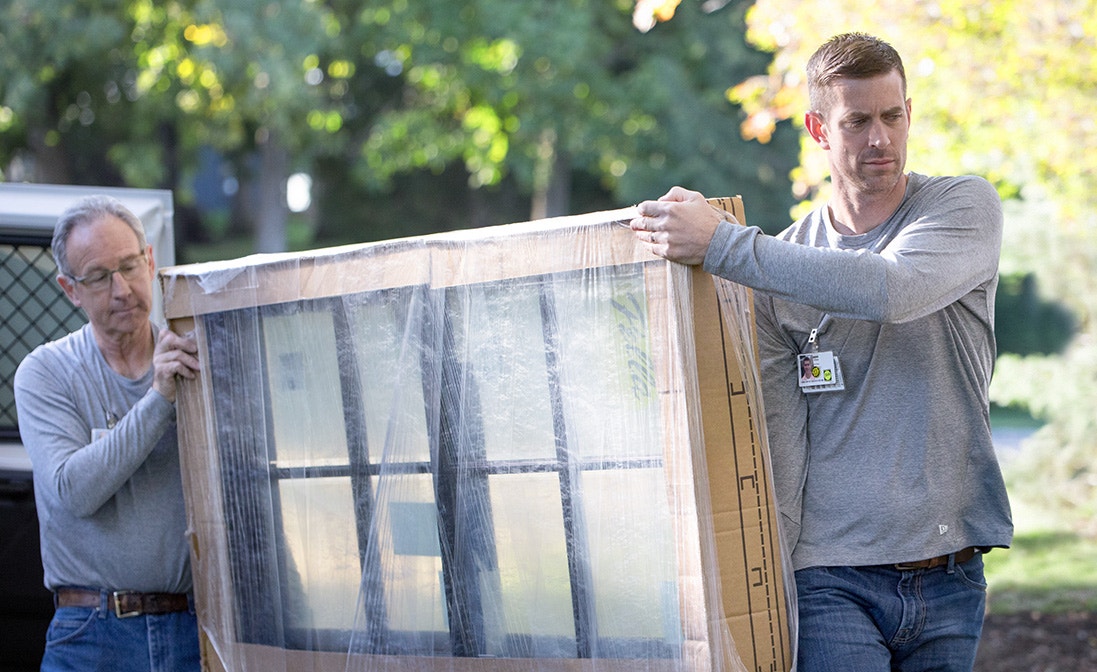 a new window, still wrapped in protective packaging, is being delivered to a home