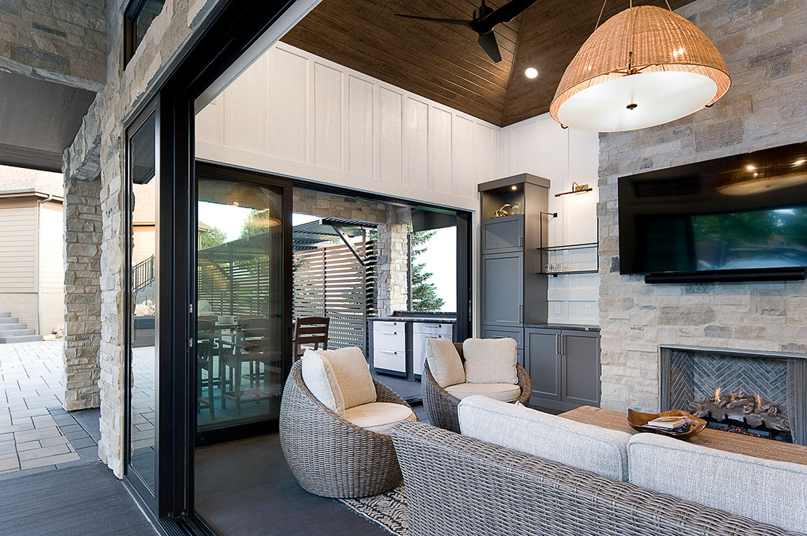 A modern living area in a pool house featuring large windows, stone walls, and comfortable seating.