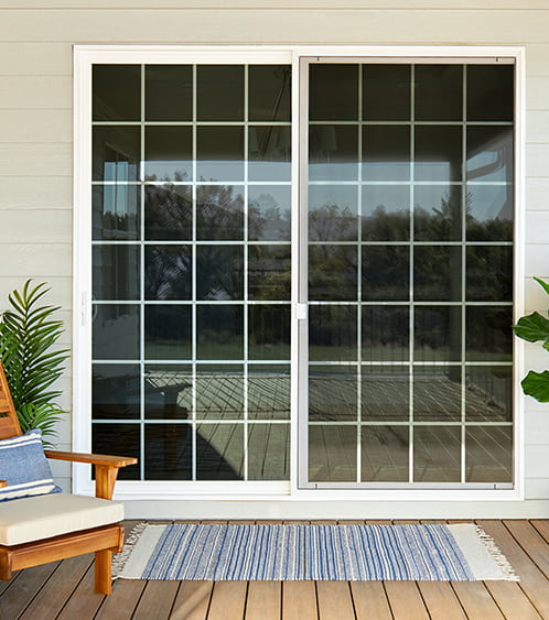 a view of a standard vinyl patio door with traditional grilles from the back deck