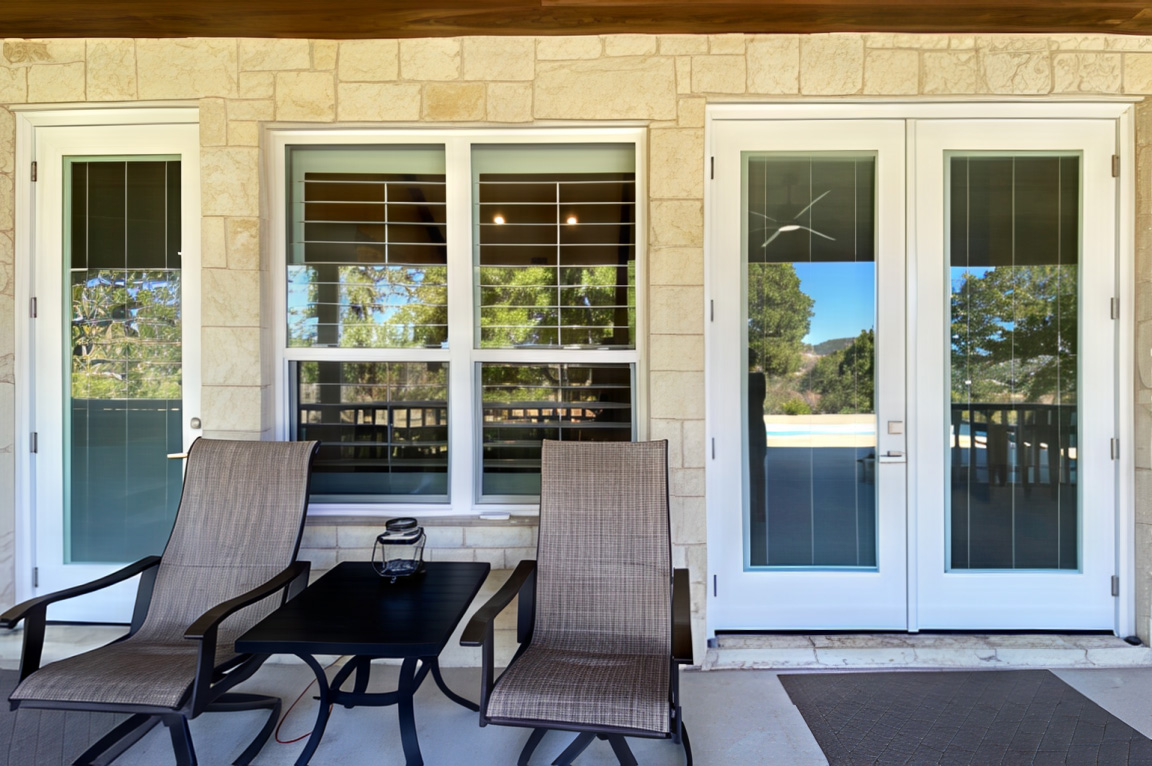 A cozy patio featuring two chairs and a coffee table, showcasing a window and patio upgrade.
