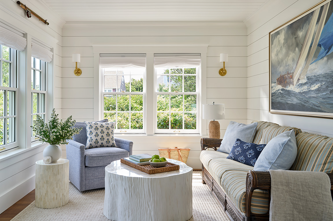 A cozy living room with white walls and traditional windows with grilles. 