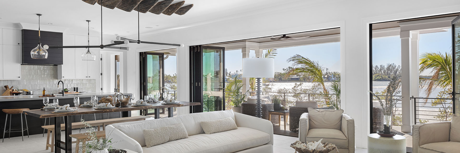 Bright coastal living and dining area with Pella sliding glass doors opening to a waterfront patio