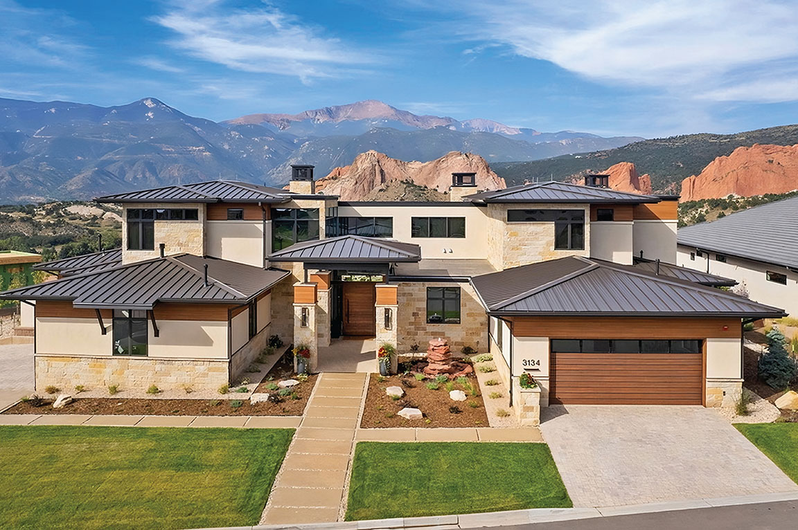 A modern house with a sleek design and mountain views, featuring large windows.