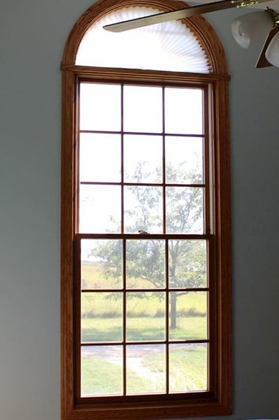 a single arched wood double-hung window behind a ceiling fan
