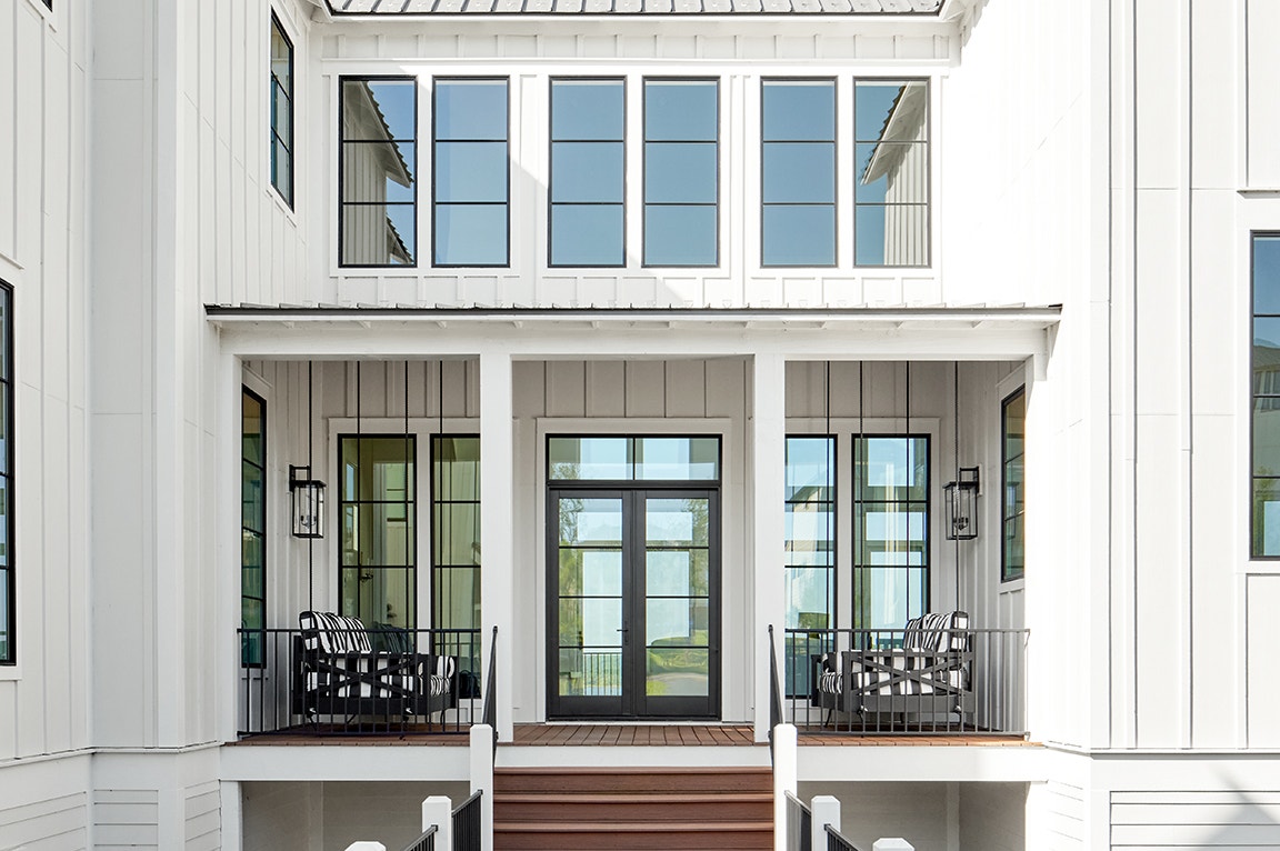 A modern home entrance featuring a porch with black and white striped chairs, showcasing standard dimensions of door.