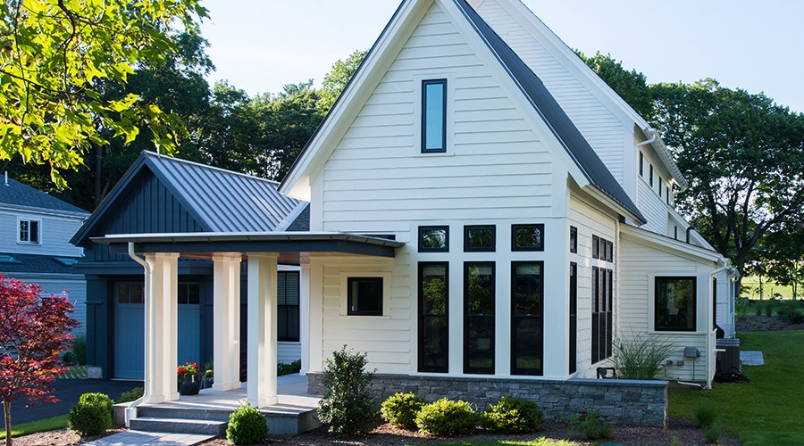 A white farmhouse-style home in Philadelphia with black narrow fiberglass windows.