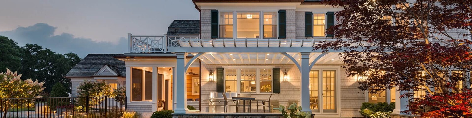 large two-story white home exterior view at dusk with porch lights on