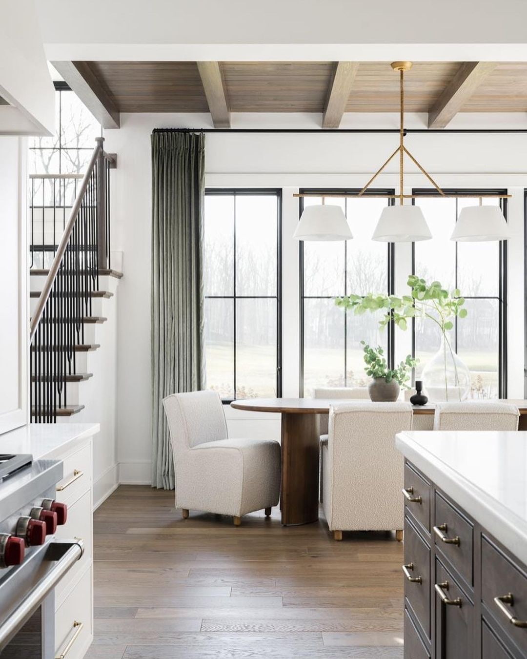 Three black windows with simple grilles stand side-by-side behind a dining table.