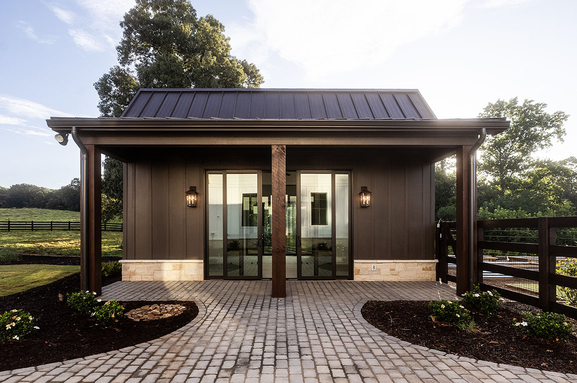 Modern pool house with brown siding and large glass doors.