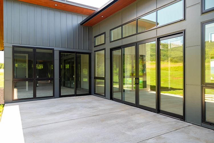 Patio view of large glass windows and patio doors on new construction home.