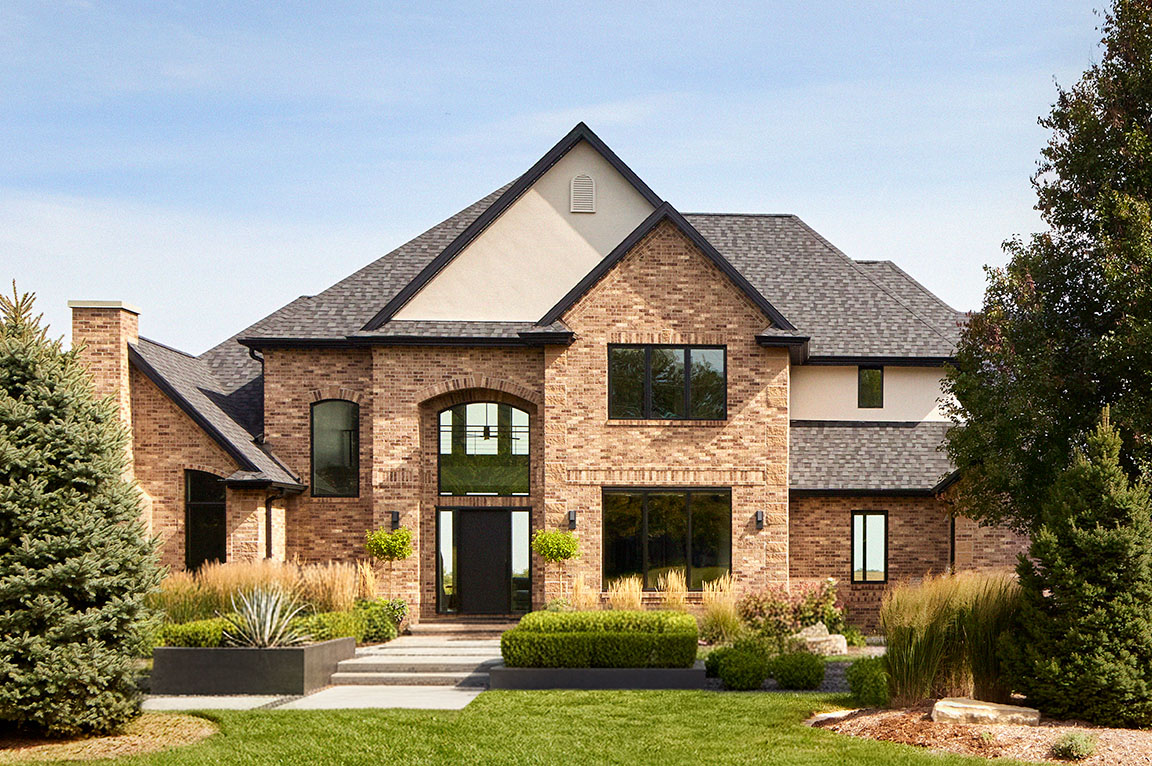 Two‑story brick home exterior featuring black‑trimmed windows, landscaped front yard, and contemporary residential design
