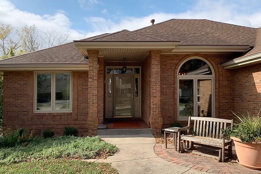 The exterior of a brick home that has updated tan windows.
