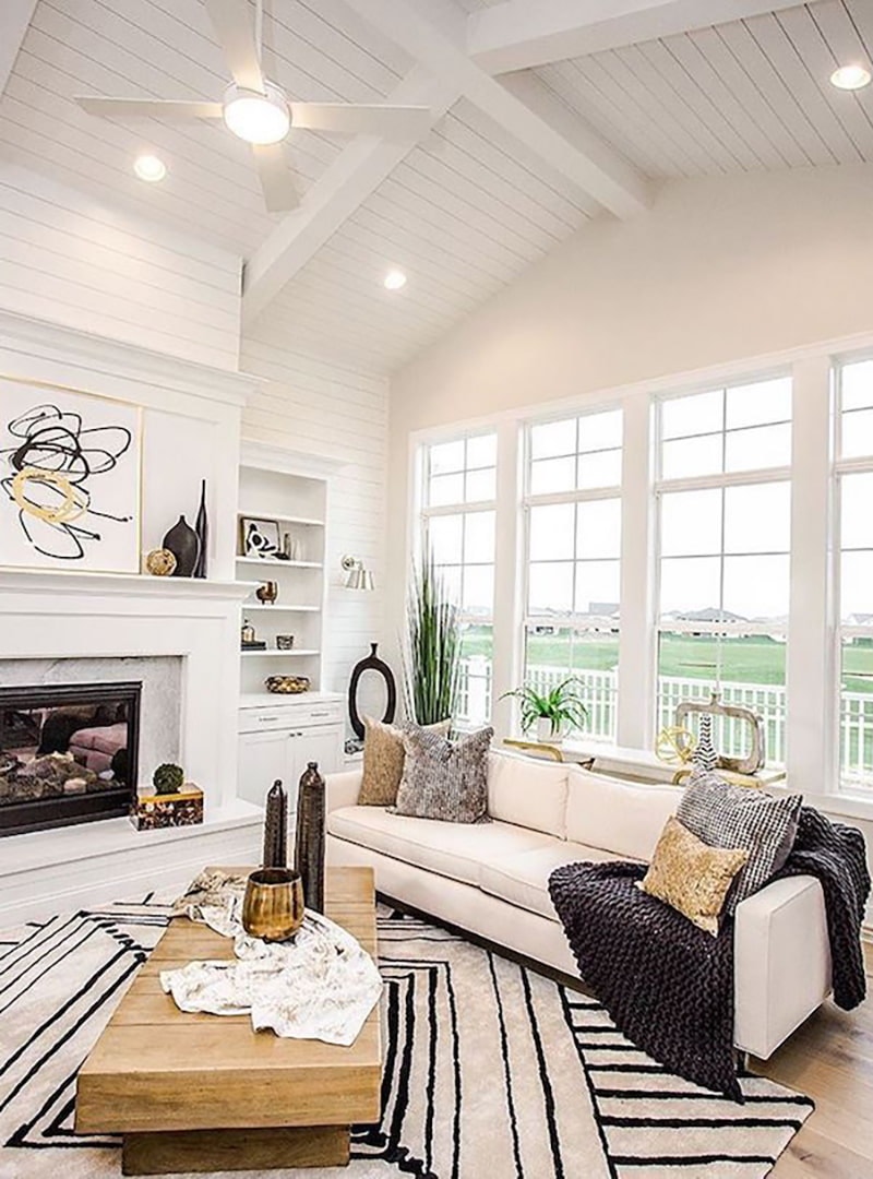 A living room has four columns of white wood double-hung windows with picture windows stacked on top.
