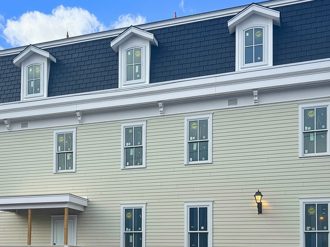 Restored historic building exterior with mansard roof, dormer windows, and light siding.