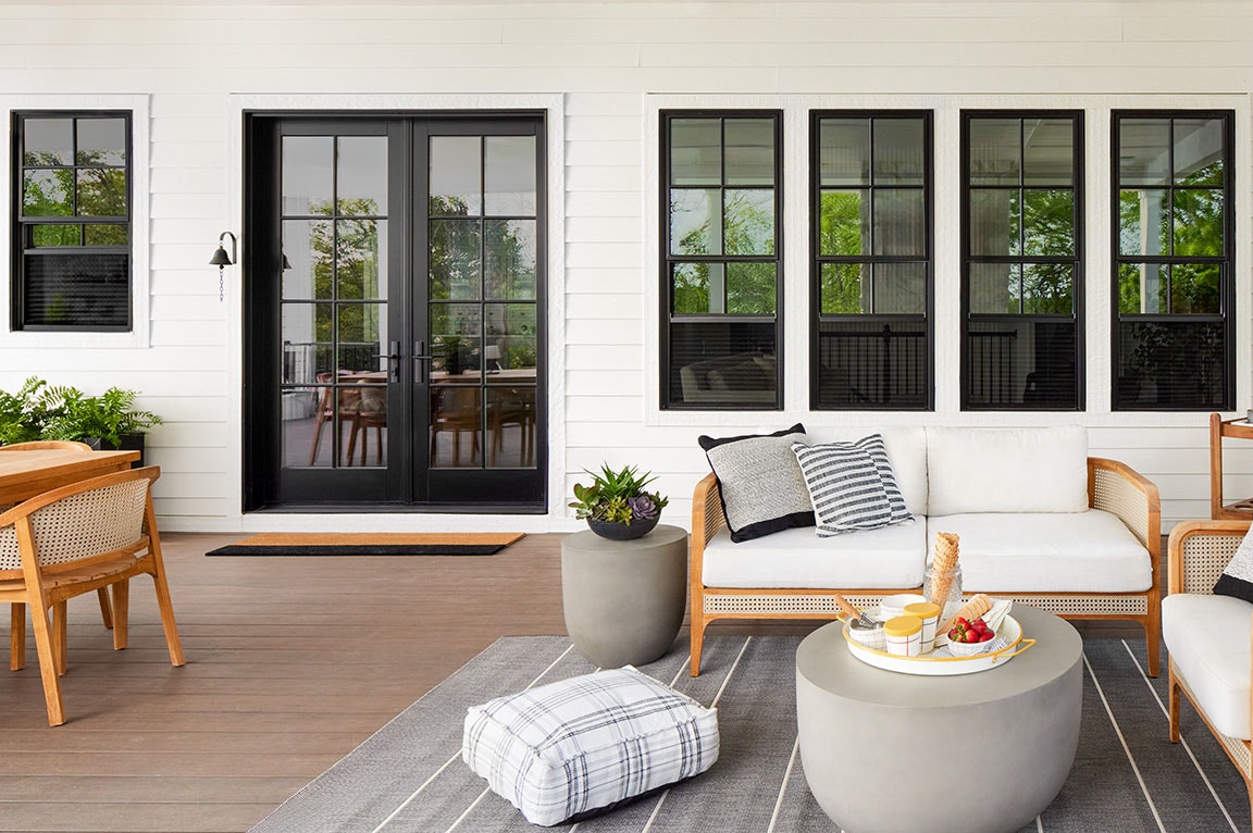 A modern patio featuring black sliding doors, stylish furniture, and a cozy atmosphere, showcasing sliding door ideas.