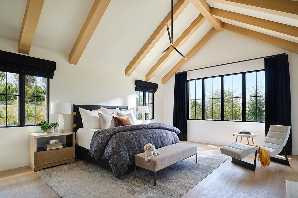 Spacious bedroom with vaulted ceiling and large black-frame windows, ideal for choosing best windows for natural light.