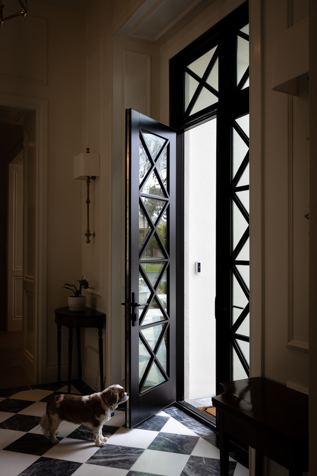 A front entryway features a custom wood front door with X-patterned grilles along with black and white tile floors.