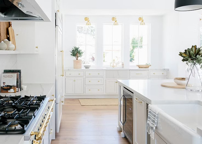 Custom kitchen with three white wood windows on the far side 